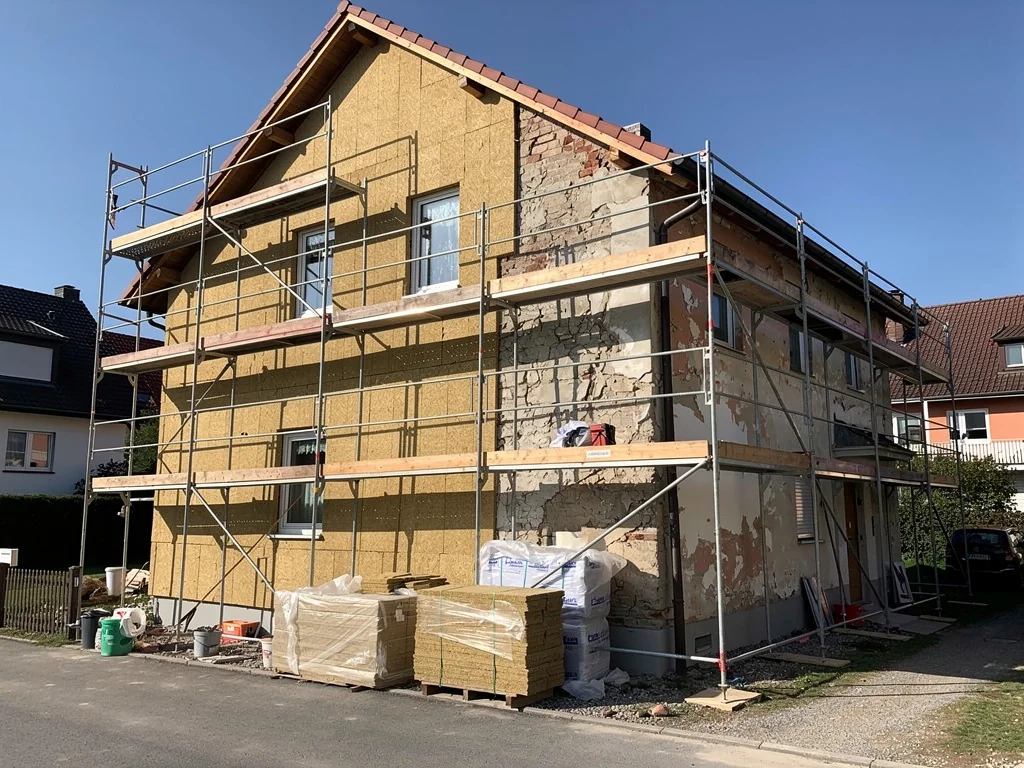 Chantier d'isolation extérieure sous échafaudage, façade en cours d'habillage en fibre de bois